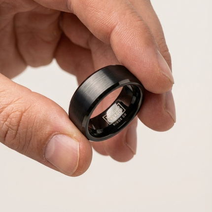 Smart ring being held between fingers on a light background