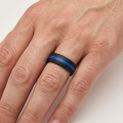 Hand wearing a black ring with a blue stripe on a light background