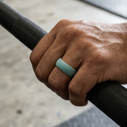 Hand holding a barbell with a greyring on a blurred gym background