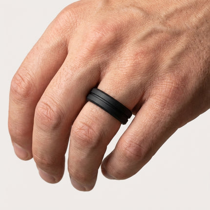 Hand wearing a black ring on a light gray background