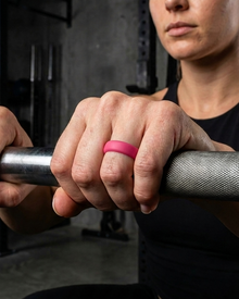 Person lifting weights with a pink fitness ring on a barbell in a gym setting