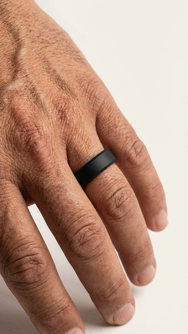 Close-up of a hand wearing a black ring on a light background