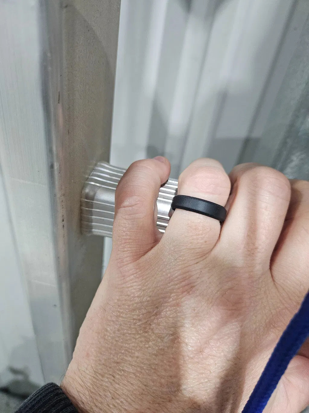 Josh’s hand gripping an aluminium ladder rung, wearing a black Ultra Thin Beveled ring